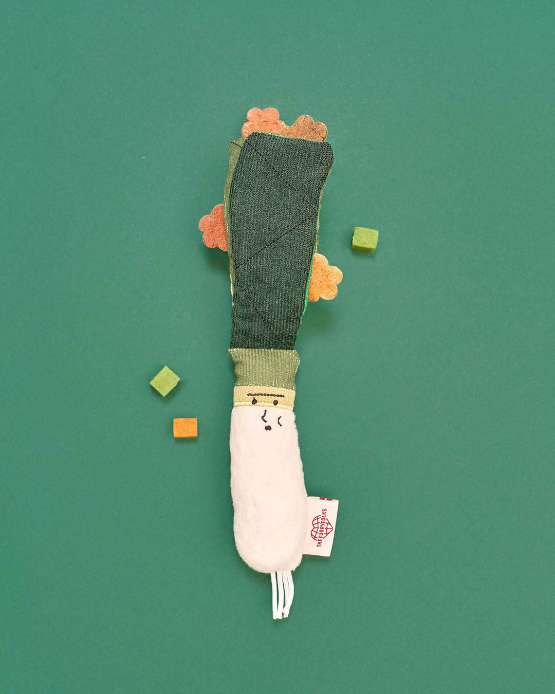 Green onion nosework plush dog toy with treats on green background