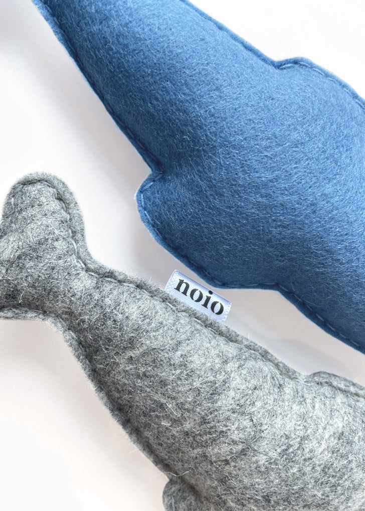 Gray and blue anchovy-shaped catnip toys, close-up of stitching.