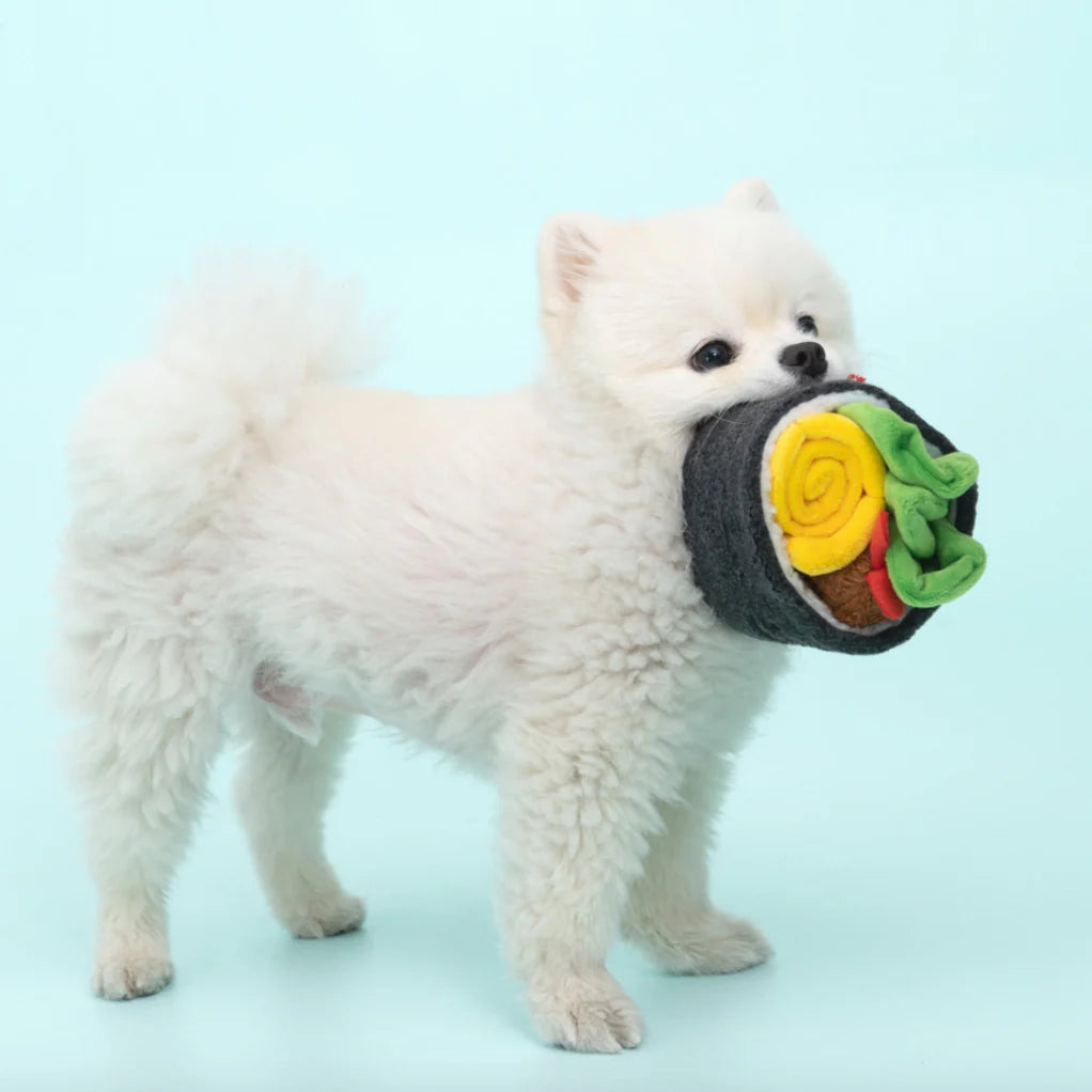 A dog playfully biting the plush shrimp of the Giant Gimbap Nosework Toy, activating the squeaker inside.