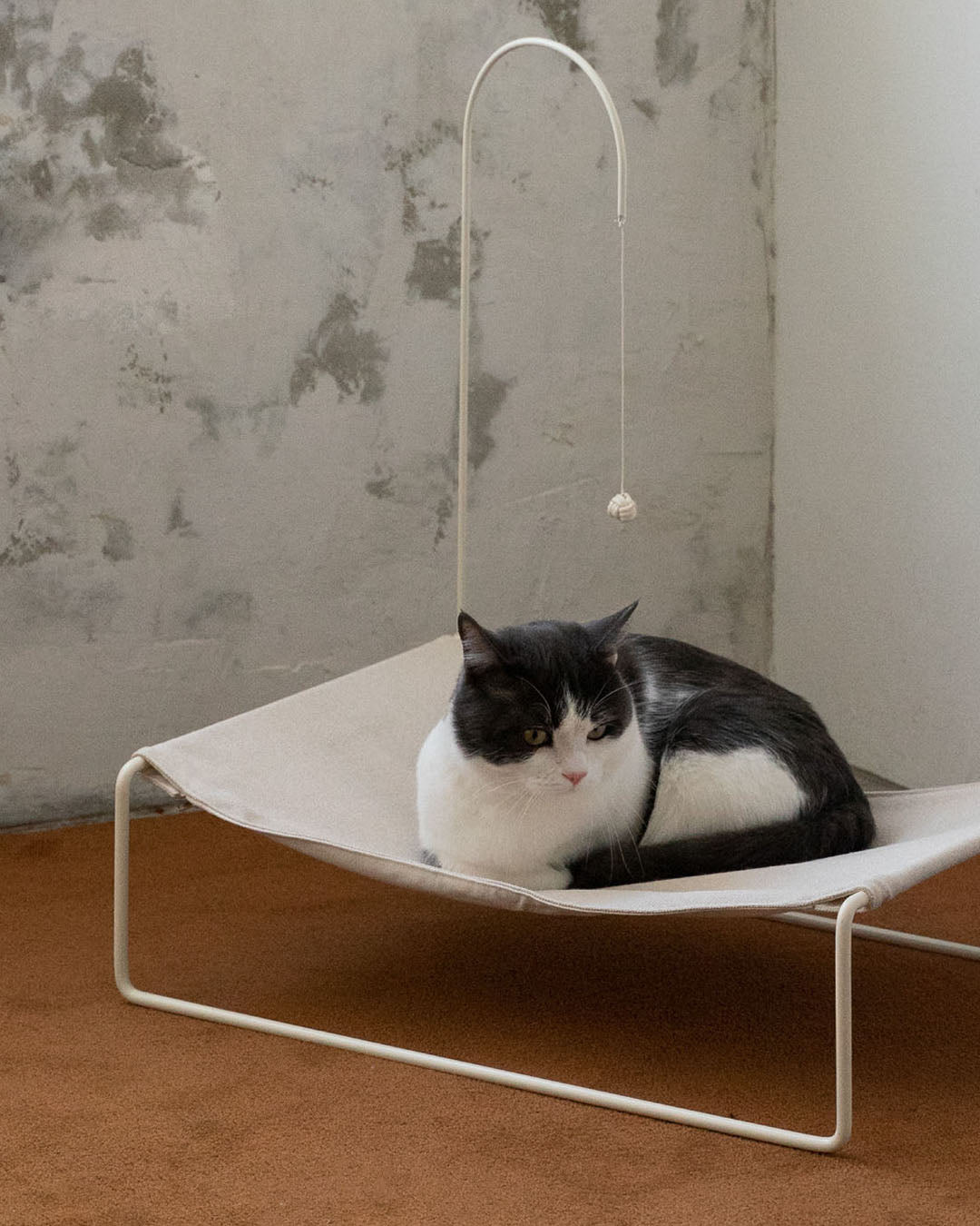 A cat stretching inside the Lullaby Hammock, enjoying the ample space and supportive fabric.