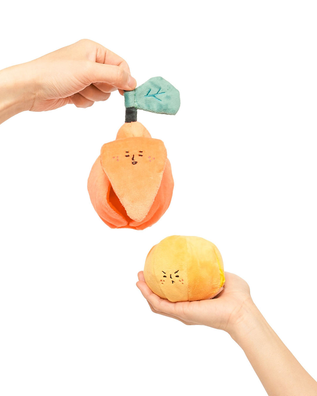 Hands holding two-piece orange nosework dog toy with removable inner orange on white background